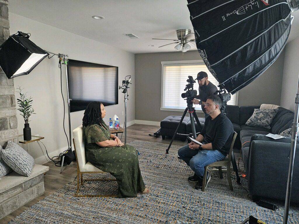 Client being filmed for a sit-down interview at home with a camera crew